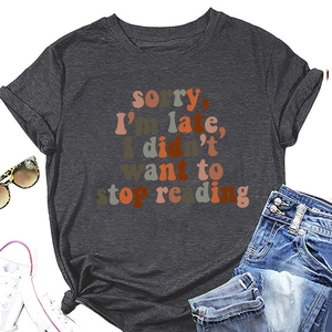 Flat lay of charcoal gray t-shirt with sorry i'm late i didn't want to stop reading print