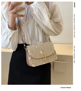 Detail of woven straw crossbody bag with floral embroidery and gold horseshoe metal lock