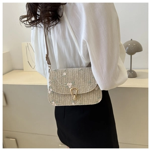 Detailed close-up of straw woven texture with delicate floral embroidery and metal buckle