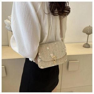 Detail of woven straw crossbody bag with floral embroidery and golden horseshoe clasp