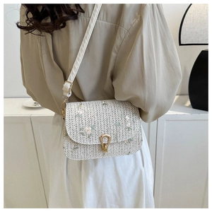 Detail of straw woven crossbody bag with pink floral embroidery and gold metal buckle