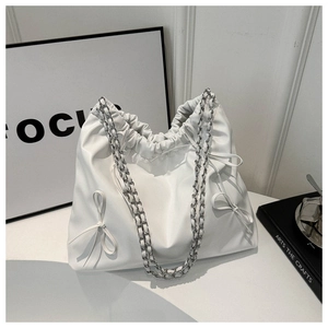 Detail of white pleated shoulder bag with delicate bows and woven chain strap accents