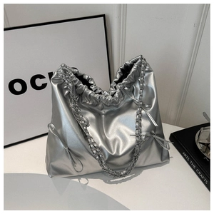 Detail of silver metallic tote bag with drawstring closure, bow and chain strap