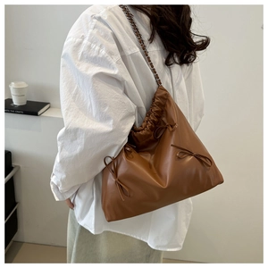 Detail of brown PU tote bag featuring drawstring pleats and three decorative bows