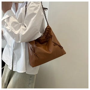 Detailed view of brown pleated leather handbag with drawstring and chain shoulder strap