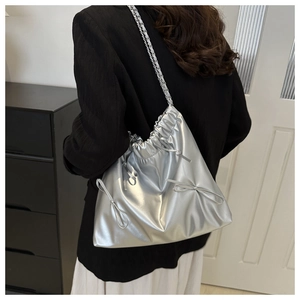 Close-up of silver pleated bucket bag with bow accents and drawstring closure detail
