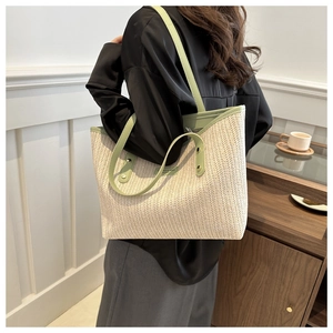 Close-up of beige woven tote bag with green leather trim and fine herringbone texture