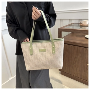 Detail showing the herringbone weave texture and green leather handle of this tote bag