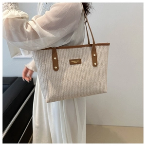 Detail of herringbone woven tote bag with dark brown leather straps and metal rivets