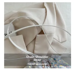 Detail of the white drawstring bucket bag featuring shiny silver sequins and a cord strap