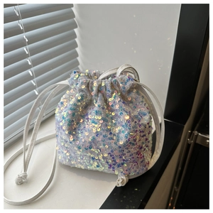 Detail of iridescent sequins on a white drawstring bucket bag with colorful reflections
