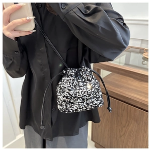 Detail of silver sequin bucket bag with drawstring closure and black leather strap