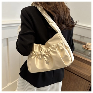 Detailed view of cream pleated shoulder bag with bow drawstring and soft leather texture