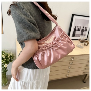 Detail of pink satin shoulder bag featuring elegant ruffles and a sweet bow decoration