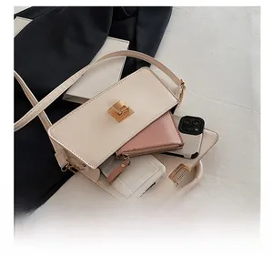 Detailansicht der cremefarbenen Umhängetasche mit rosa Brieftasche und Smartphone