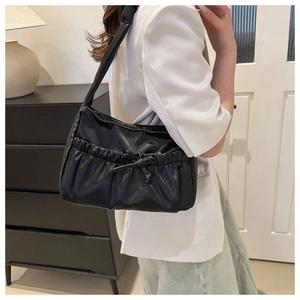 Detail of black pleated shoulder bag with decorative bow and premium matte texture finish