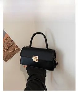 Detailansicht des goldenen Metalldrehverschlusses an der schwarzen Kunstleder-Handtasche
