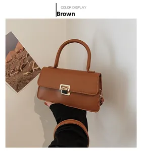 Detailaufnahme der braunen matten Ledertasche mit goldenem Metallschloss und Tragegriff