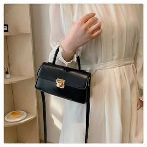 Detail of vintage black leather crossbody bag featuring an elegant gold metallic lock