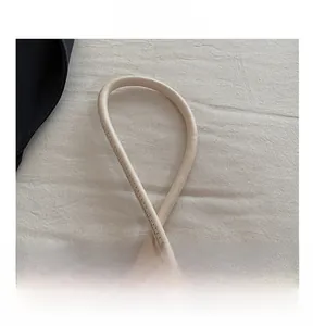 Dettaglio del manico in pelle beige con cuciture precise di una borsa a spalla minimalista