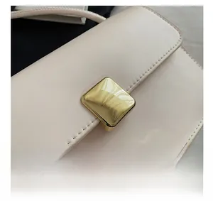 Dettaglio della borsa in pelle beige con fibbia quadrata dorata e cuciture di precisione