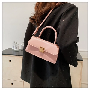 Close-up of pink leather handbag with gold metal clasp and adjustable shoulder strap