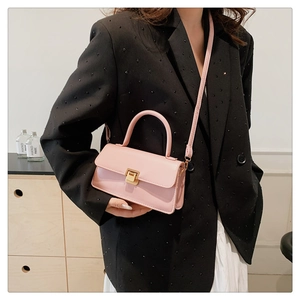 Detailed close-up of a pink mini crossbody bag with gold lock and thin shoulder strap