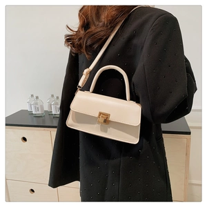 Detail of a creamy beige square crossbody bag with gold buckle and smooth PU texture