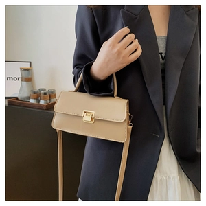 Detail der beigen quadratischen Handtasche mit goldener Schnalle und schmalem Gurt