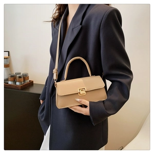 Elegante beige Henkeltasche mit goldenem Schlossverschluss in stilvollem Lifestyle-Ambiente