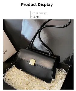 Dettaglio della borsa a tracolla nera minimalista con fibbia dorata in confezione regalo