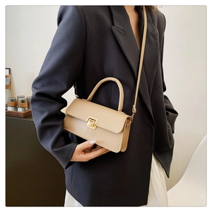 Detail view of a cream-colored square crossbody bag featuring a golden metallic lock