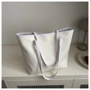 Minimalist white tote bag detail showing smooth leather texture and gold rivet hardware