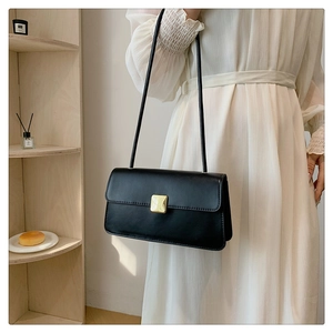 Dettaglio della chiusura quadrata dorata su una borsa minimalista in pelle nera vintage