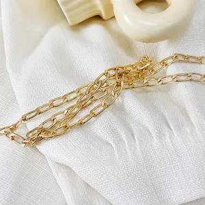 Close-up of a high-quality gold metal chain strap on white textured fabric for evening bags