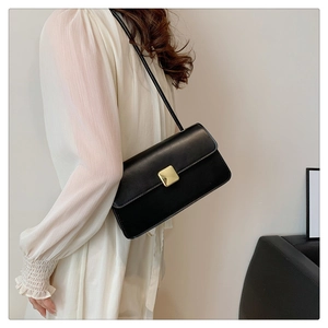 Vue latérale du sac bandoulière en cuir noir avec boucle carrée dorée minimaliste