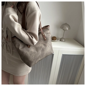 Detail of dark brown vintage textured tote bag with golden rivets and shoulder strap