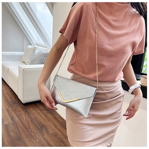 Detail of silver sequin envelope clutch bag with gold V-metal trim and chain strap