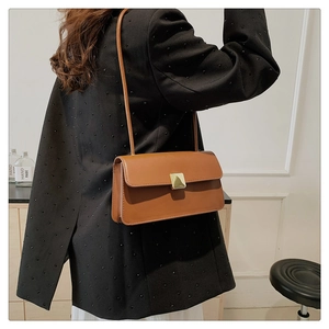 Dettaglio borsa vintage in pelle marrone con elegante chiusura a scatto dorata quadrata