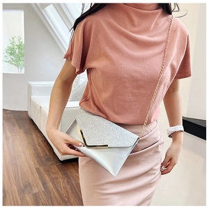 Silver sequin envelope clutch bag with V-shaped metal trim worn over the shoulder