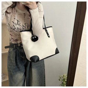 Mirror selfie showing canvas tote bag with black leather trim and plush soot sprite charm