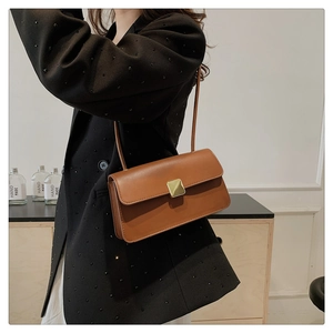 Détail d'un sac bandoulière marron en cuir avec fermoir doré et fine lanière de luxe