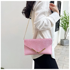 Detail of pink sequin envelope clutch featuring V-shaped gold metal trim and chain strap