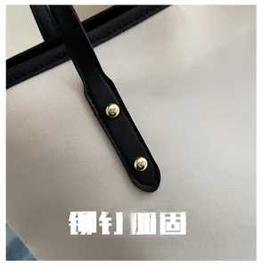 Detailed shot of sturdy black leather handles with gold rivet reinforcement on canvas bag