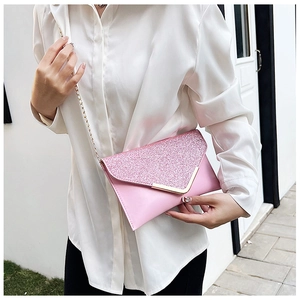 Detail of pink sequin envelope clutch with gold V-metal trim and chain strap on model