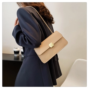 Dettaglio borsa a tracolla quadrata albicocca con chiusura dorata su blazer blu navy