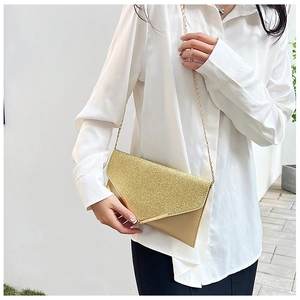 Close-up of golden sequin envelope clutch bag with elegant chain strap worn by a model