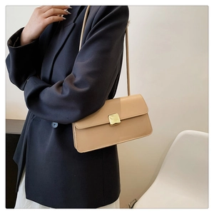 Détail du sac beige minimaliste avec fermoir métallique doré carré sur cuir texturé chic