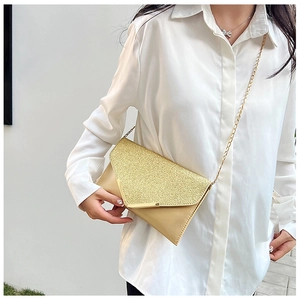 Detail of glitter evening clutch bag with champagne gold sequins and V-shaped metal trim