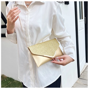 Macro view of sparkly gold sequin envelope clutch bag with fine metal shoulder chain